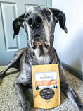 Load image into Gallery viewer, Chicken Hearts small-animal treats by Naked Beasts in a yellow package with a dog in the foreground.