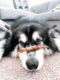 Load image into Gallery viewer, Chicken feet by Naked Beasts; brown chicken foot resting on carpet in front of a black-and-white dog.
