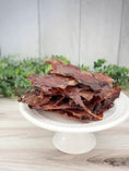 Load image into Gallery viewer, Beef Lips (Fat Trimmed) Thin Cut jerky slices; reddish-brown on a white pedestal plate