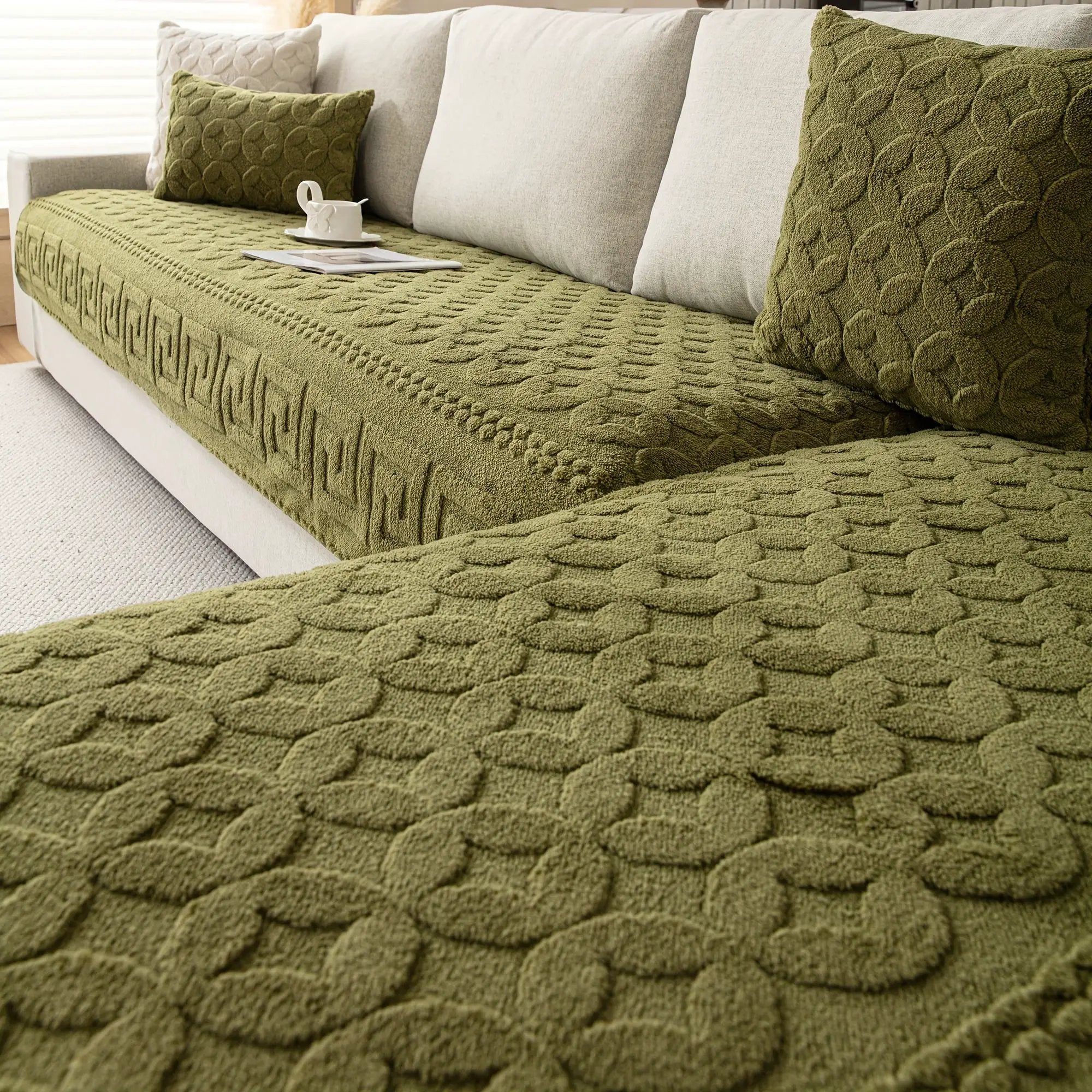 L-shaped green couch cover on beige sofa with two matching cushions