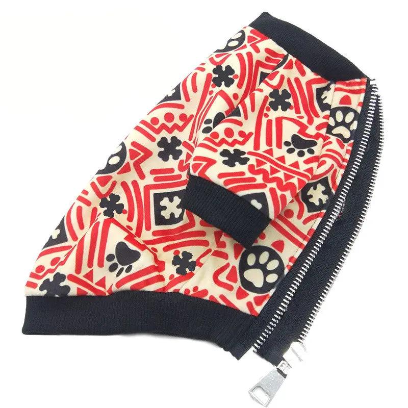 Dog jacket with red and cream geometric print featuring paw shapes, navy ribbed trim and a silver zipper