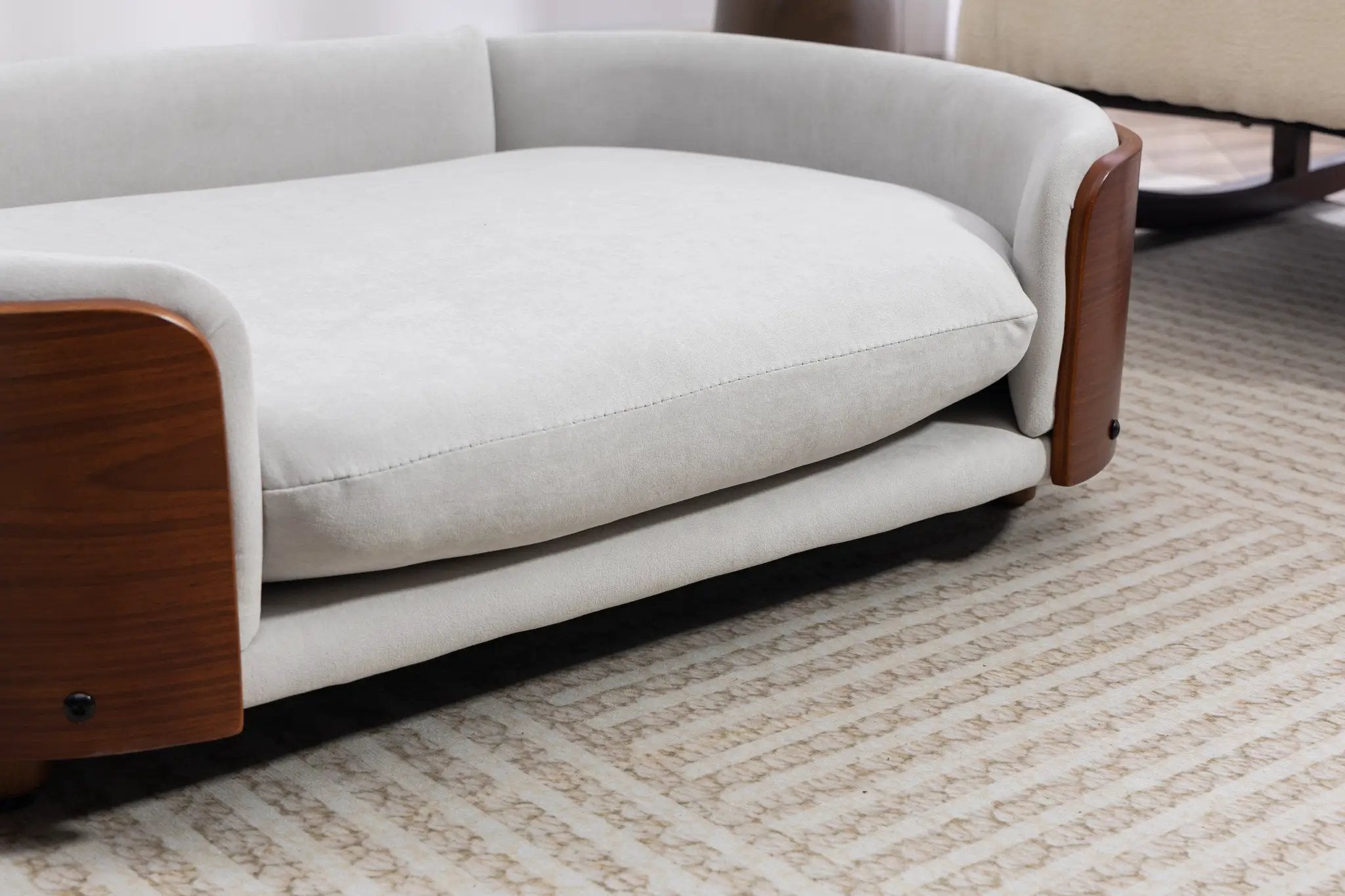 Scandinavian style elevated dog bed by Home Furnishers with solid wood legs and light gray upholstery.