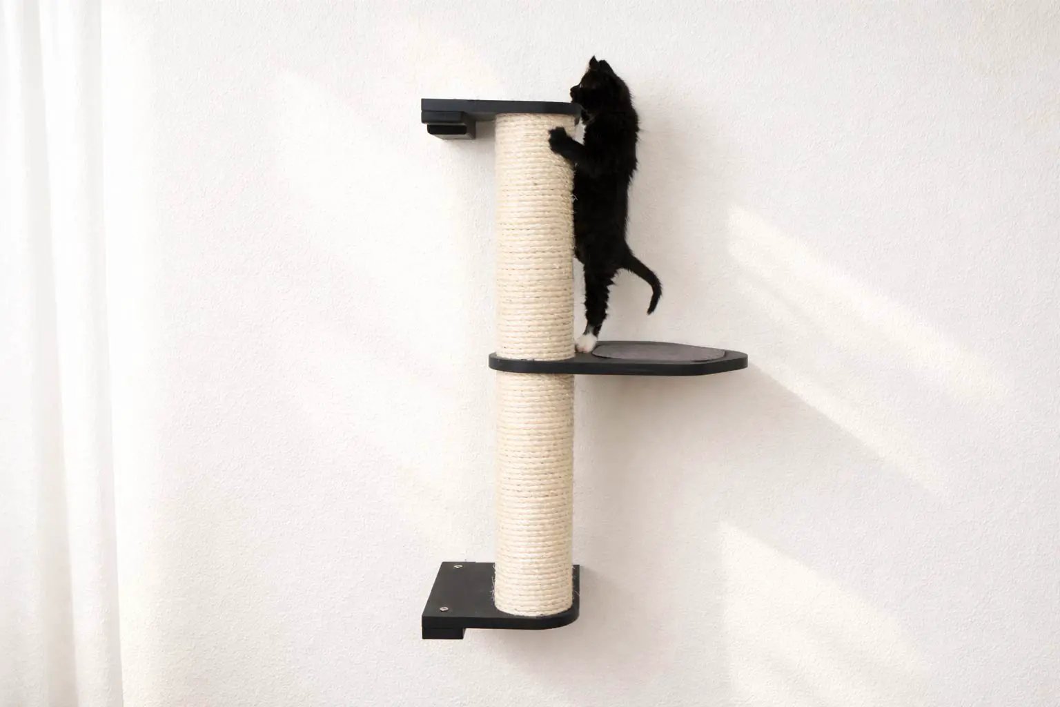 Wall-mounted cat climbing pole with natural sisal rope and a round black shelf