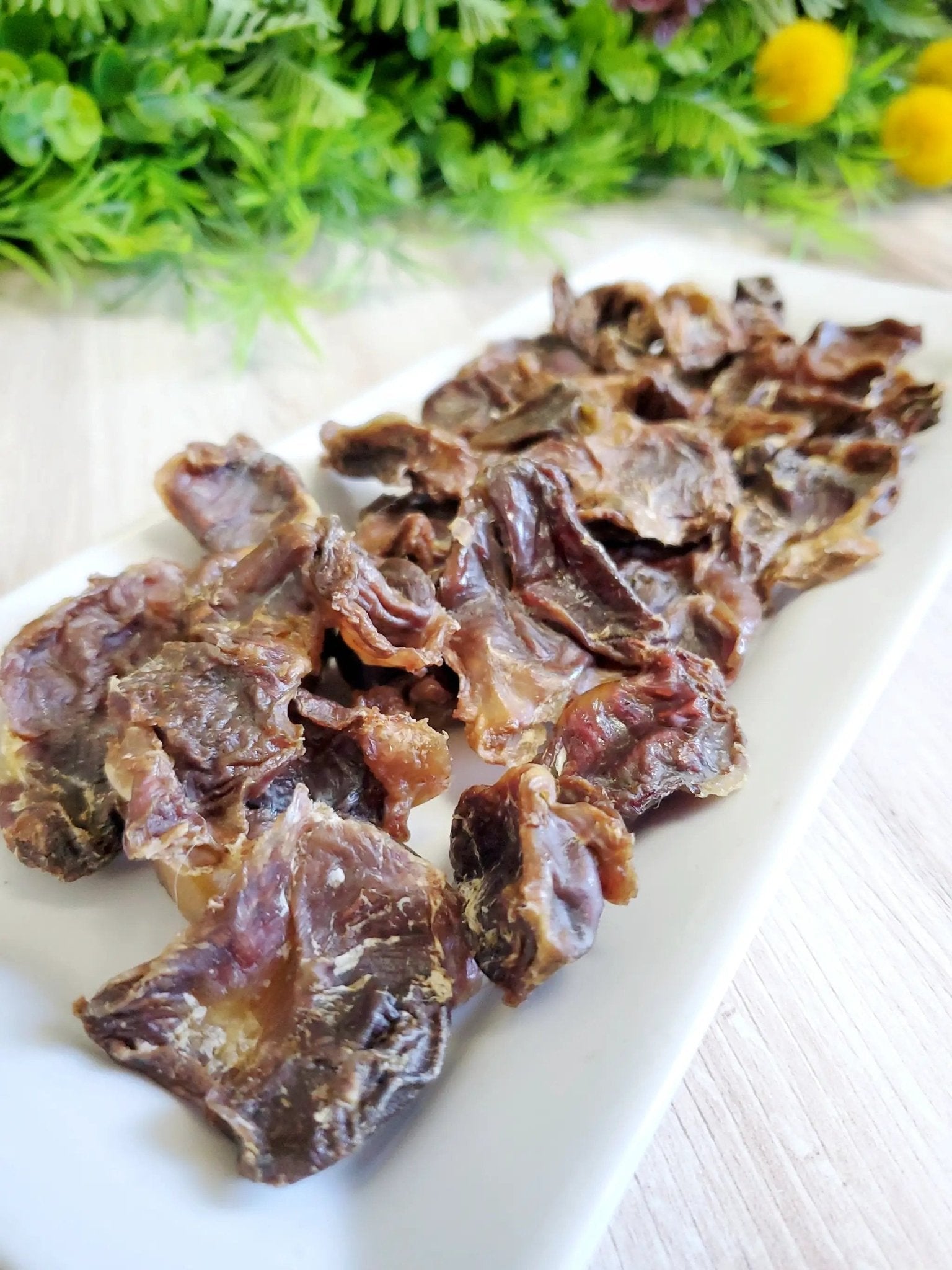 Chicken gizzards by Naked Beasts on a white platter, several browned cooked pieces