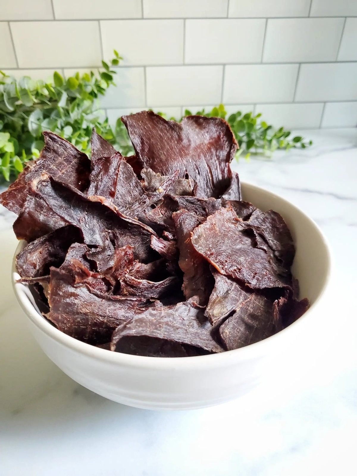 Beef heart thin-cut slices, fat-trimmed, dark red in a white bowl