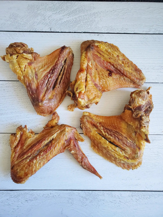 Turkey wings, fried to crispy golden brown; five pieces on a white wooden surface.