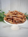 Load image into Gallery viewer, Pheasant feet on a white pedestal plate; dried brown meat snacks.
