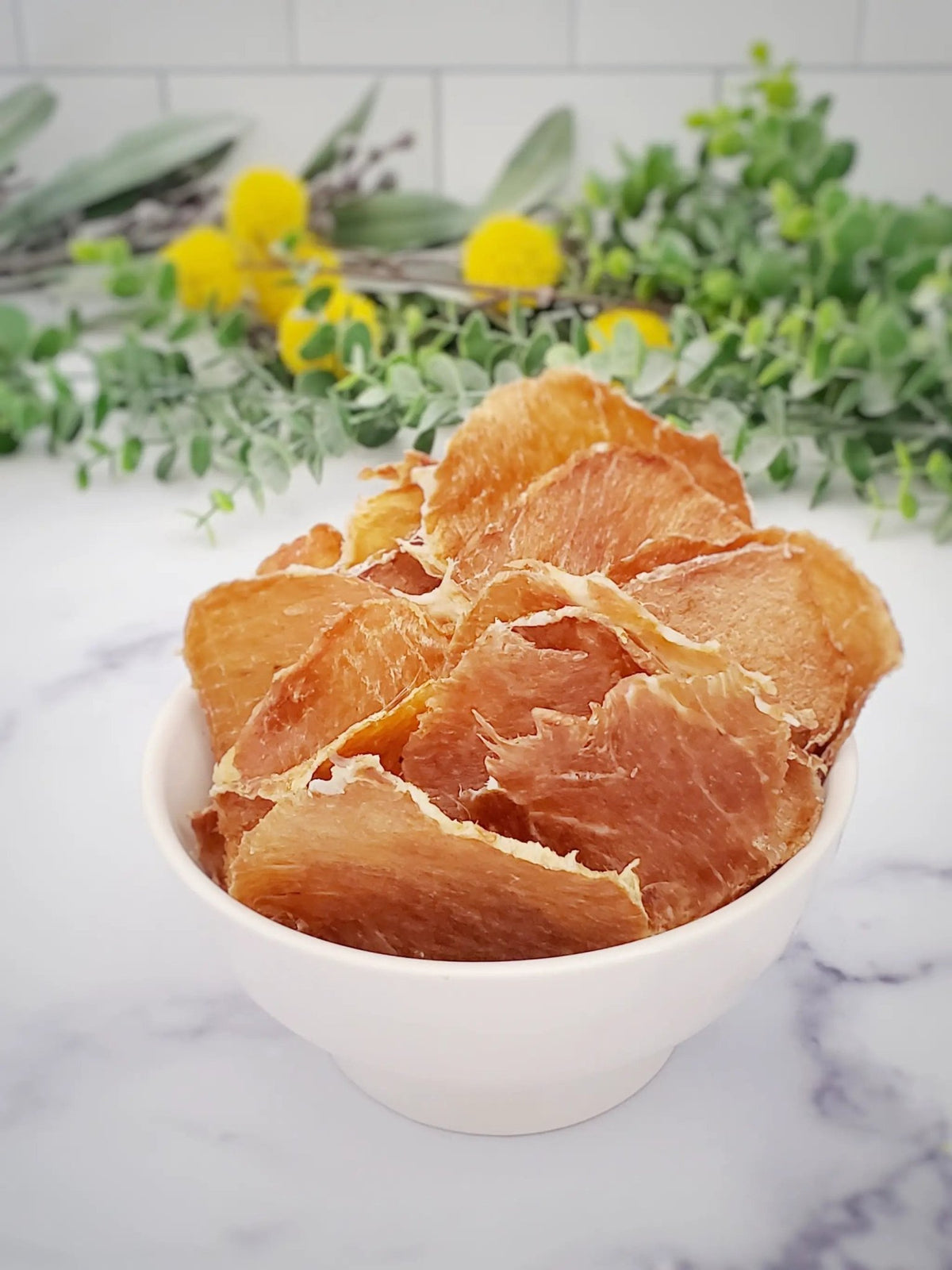 Pork Loin Fat-Trimmed Thin-Cut slices by Naked Beasts in a white bowl with green herbs in the background