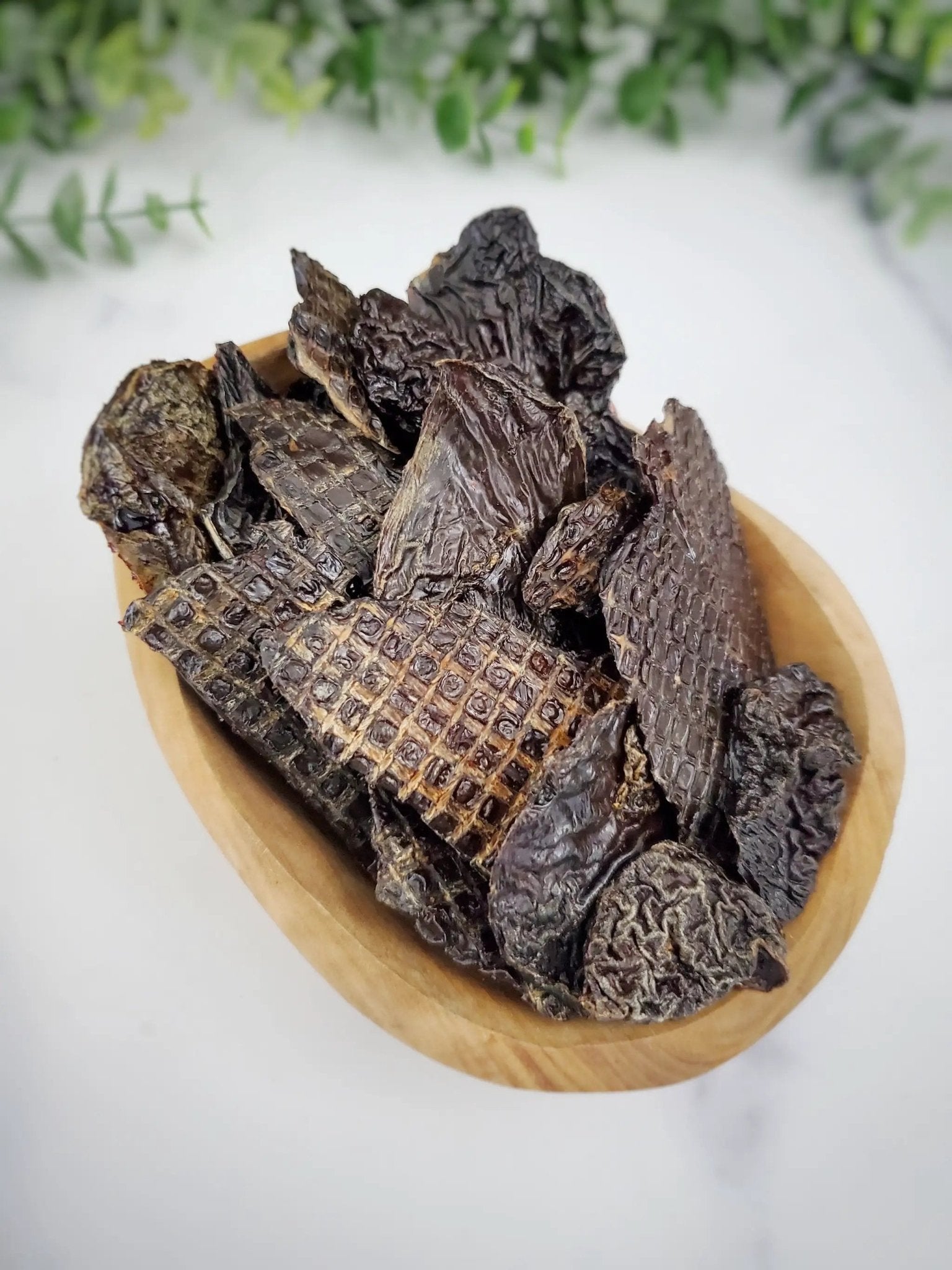 Turkey liver small animal treats by Naked Beasts, dark brown jerky slices in a wooden bowl