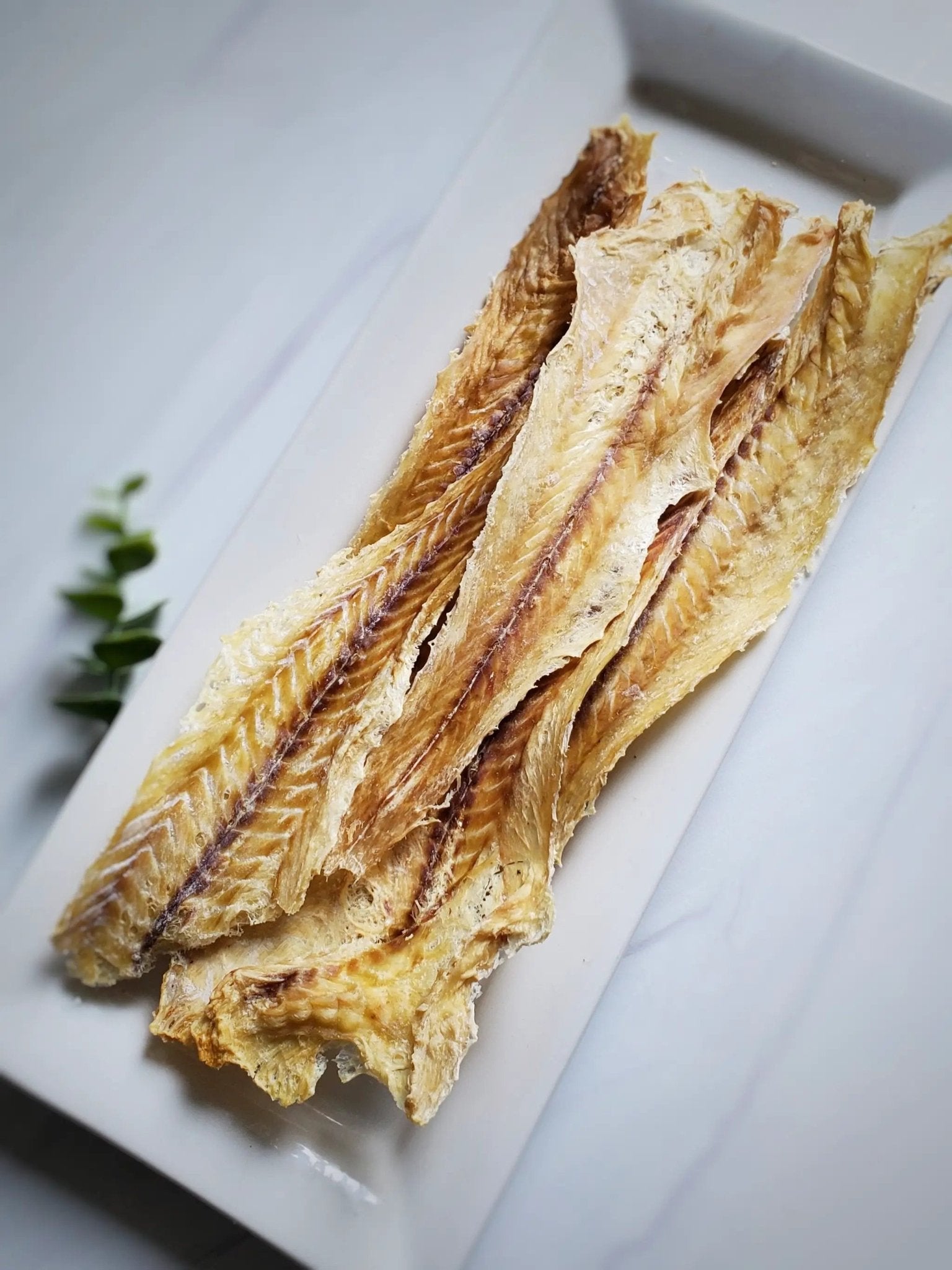 Pollock fillets, wild-caught, four golden-brown dried pieces on a white plate