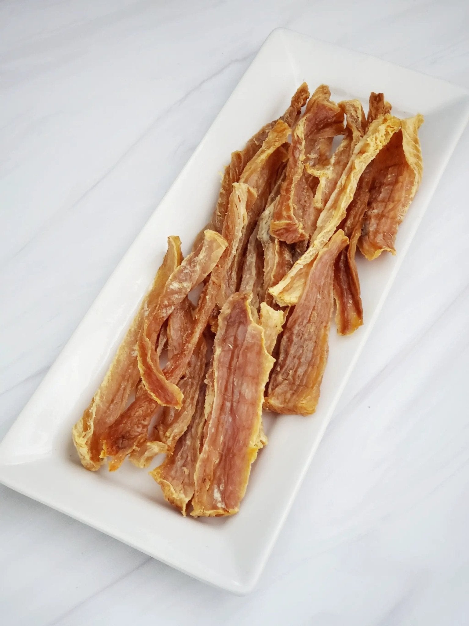 Hoki (Wild-Caught) dried fish strips on a white plate