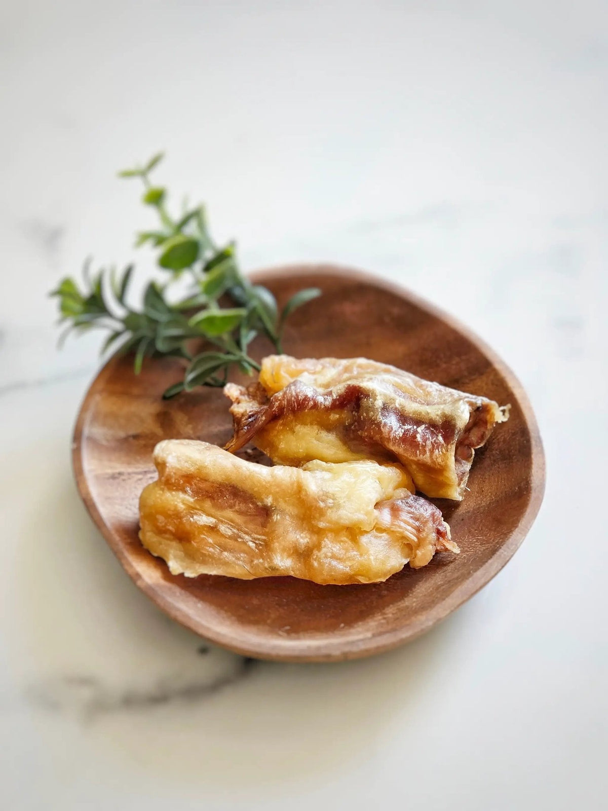 Beef tendon pieces (whole & halved) on a wooden plate with thyme sprigs