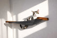 Load image into Gallery viewer, Hanging Cat Bed Hammock with gray fabric and wooden supports on a wall, cat resting on it
