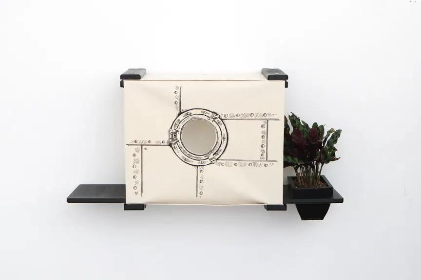 Deluxe Cat Cubby Bed beige fabric with riveted panel design and circular porthole on a wall shelf