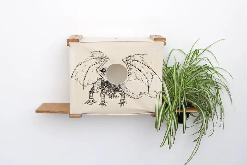 Deluxe Cat Cubby Bed by Catastrophic Creations; beige fabric cubby with round entrance, wood shelves, dragon art, plant