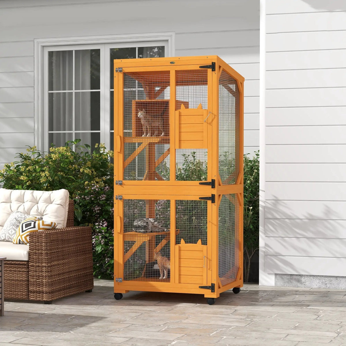 Orange PawHut loft-style cat enclosure on a patio, with cats on raised platforms behind mesh doors