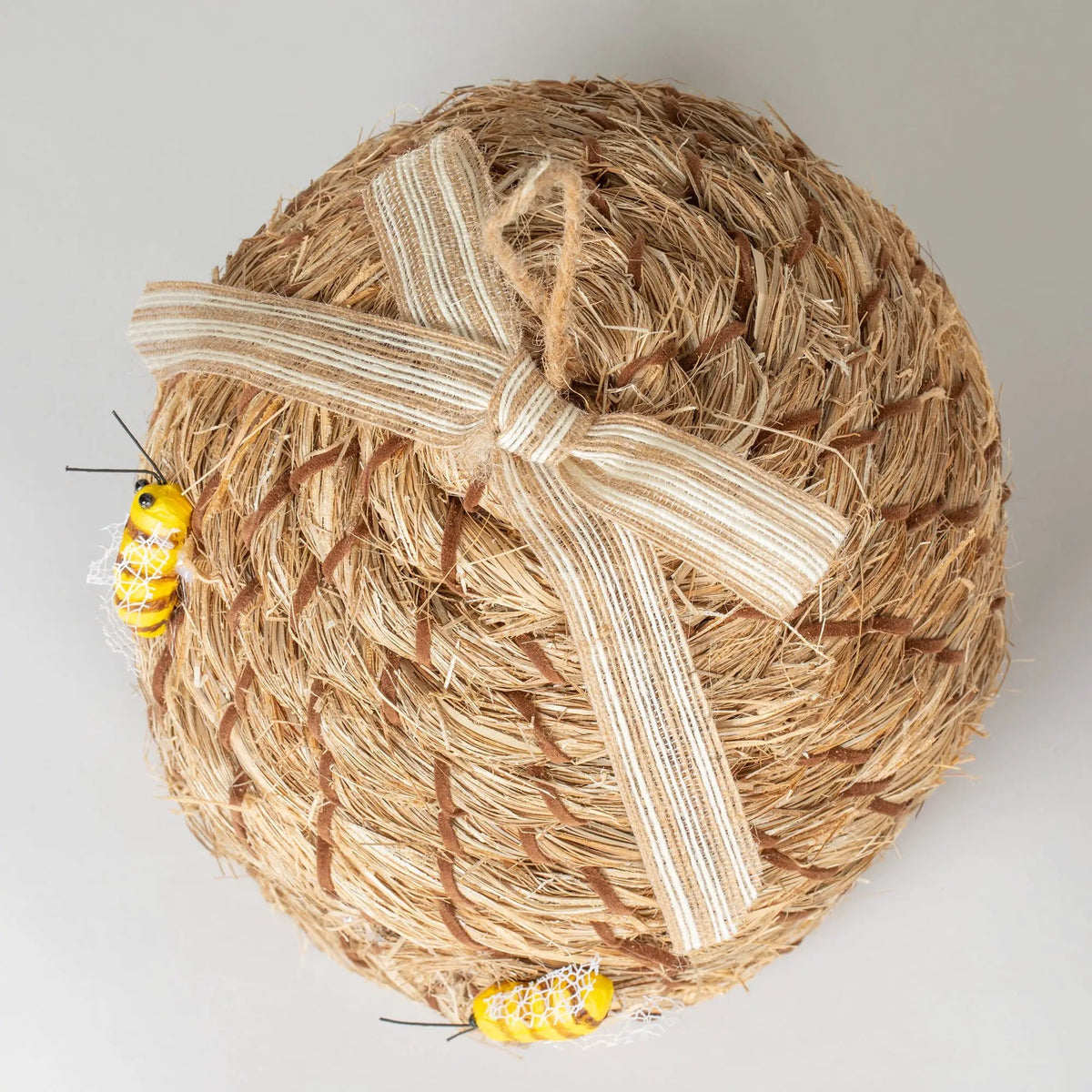 Beehive birdhouse with natural straw texture, brown accents, and striped ribbon