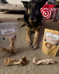 Load image into Gallery viewer, Beef Tendon (Whole & Halved) dog treats by Naked Beasts in a clear bag and beige pouch beside a German Shepherd

