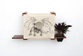 Carica l'immagine nel visualizzatore della galleria, Deluxe Cat Cubby Bed with beige fabric and dragon illustration, mounted on dark wooden shelves.

