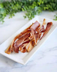 Carica l'immagine nel visualizzatore della galleria, Pig ears, several brown dried strips on a white rectangular plate
