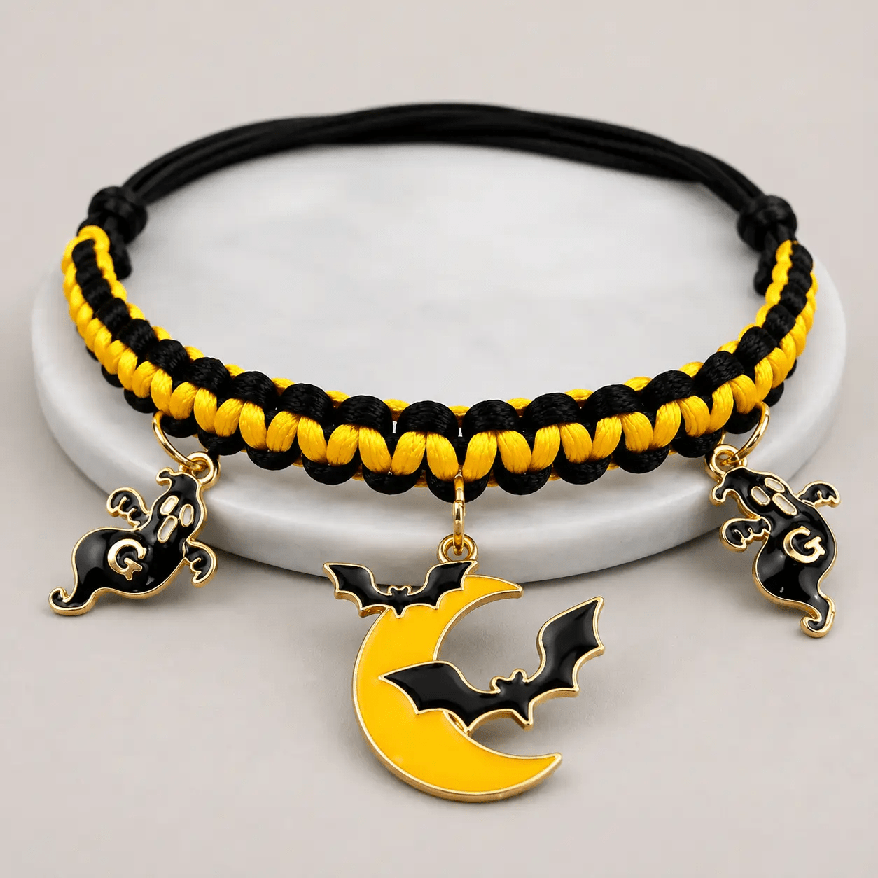 Halloween hand-woven pet collar decoration in black and yellow with three charms: bat, moon, ghost.