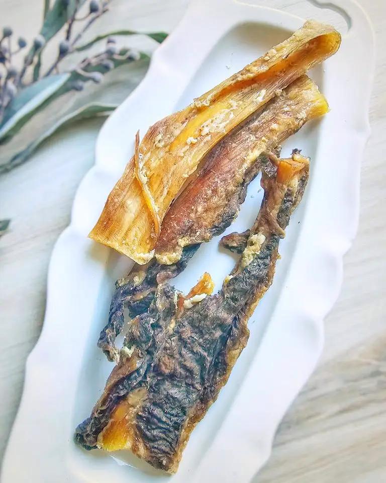 Beef backstrap jerky for small animals, grass-fed and fat-trimmed; two long strips on a white plate.