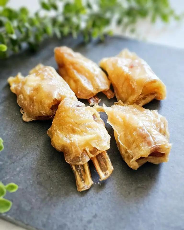 Beef tendon pieces, whole and halved, golden-brown cooked tendons with exposed bone ends on a dark plate