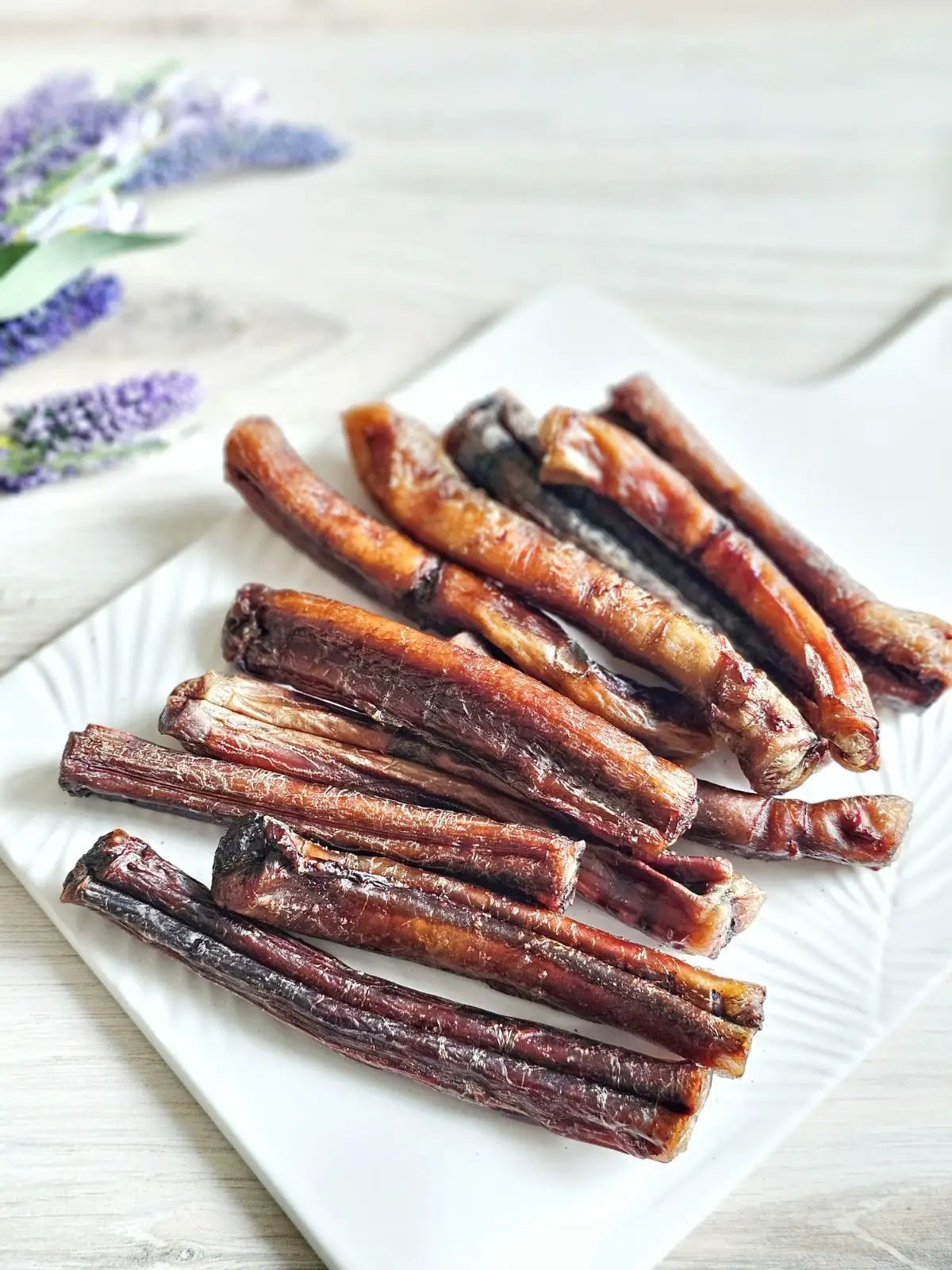 Beef pizzle sticks on a white plate; dried brown-red treats, Limited Edition by Naked Beasts