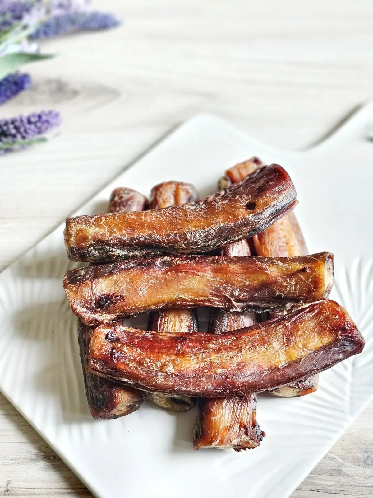 Naked Beasts beef pizzle sticks, short dried brown chews on a white plate; multiple pieces, limited edition