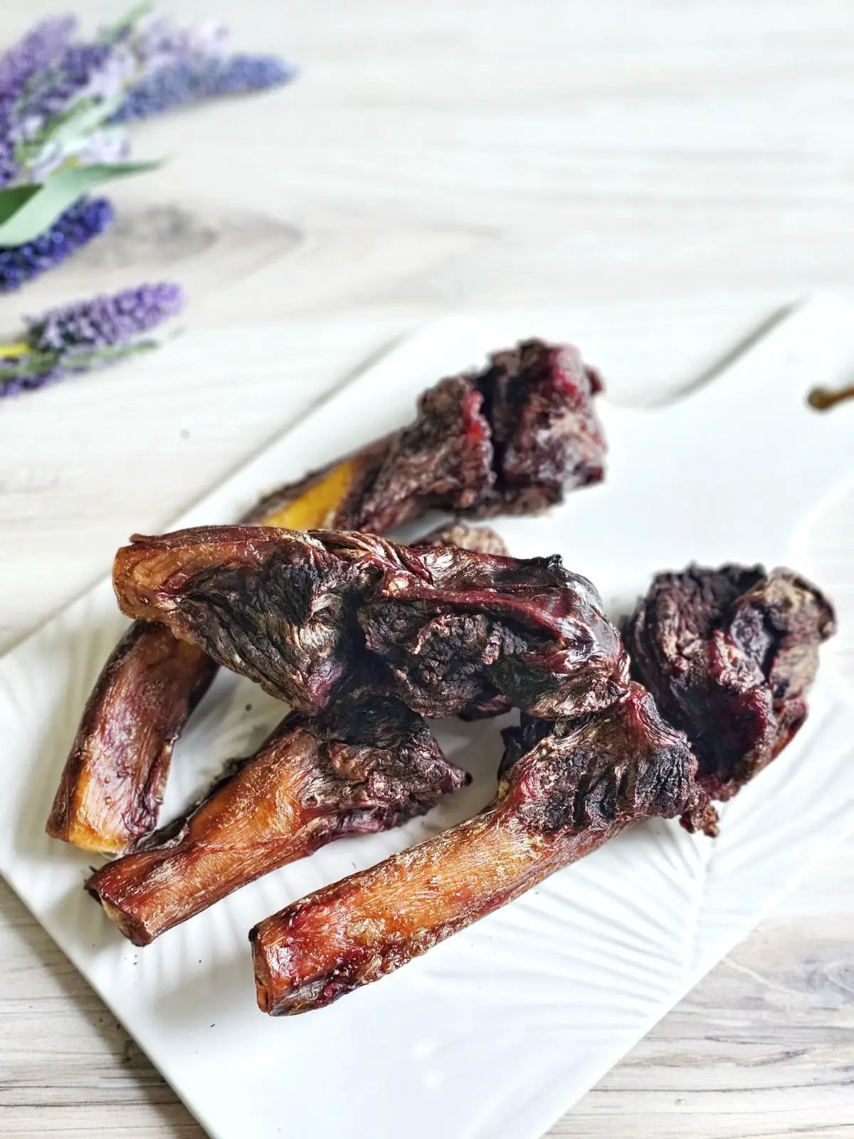 Naked Beasts beef pizzle sticks (4 pieces) on a white plate; dark brown, dried chews