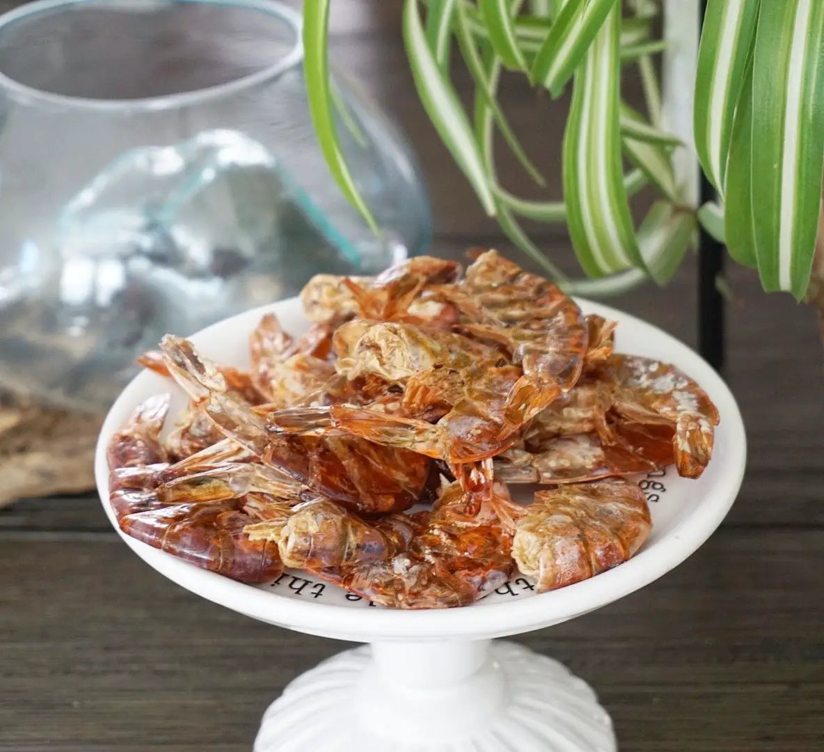 Shrimp on a white pedestal plate; cooked, reddish-brown shells.