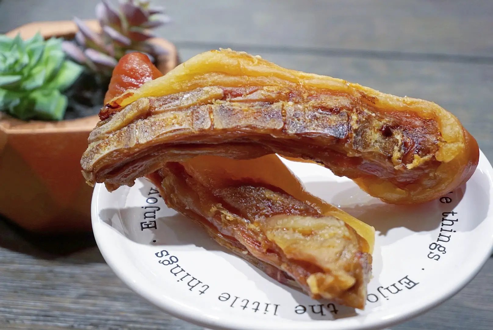 Pork tails by Naked Beasts, two pieces on a plate with golden-brown glaze and crispy fat.