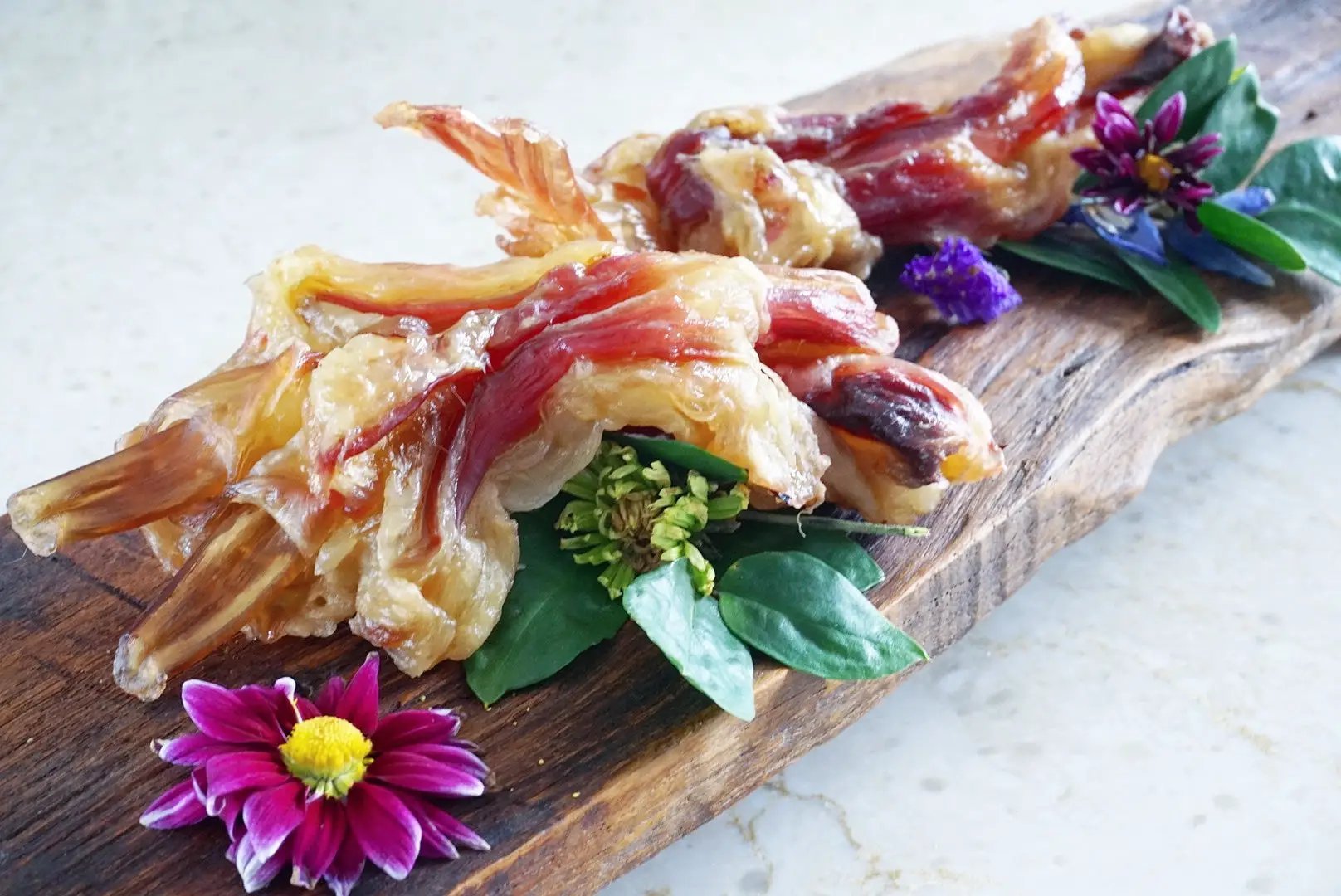 Beef Tendon (Whole & Halved) on a rustic wooden board with green leaves and purple flowers