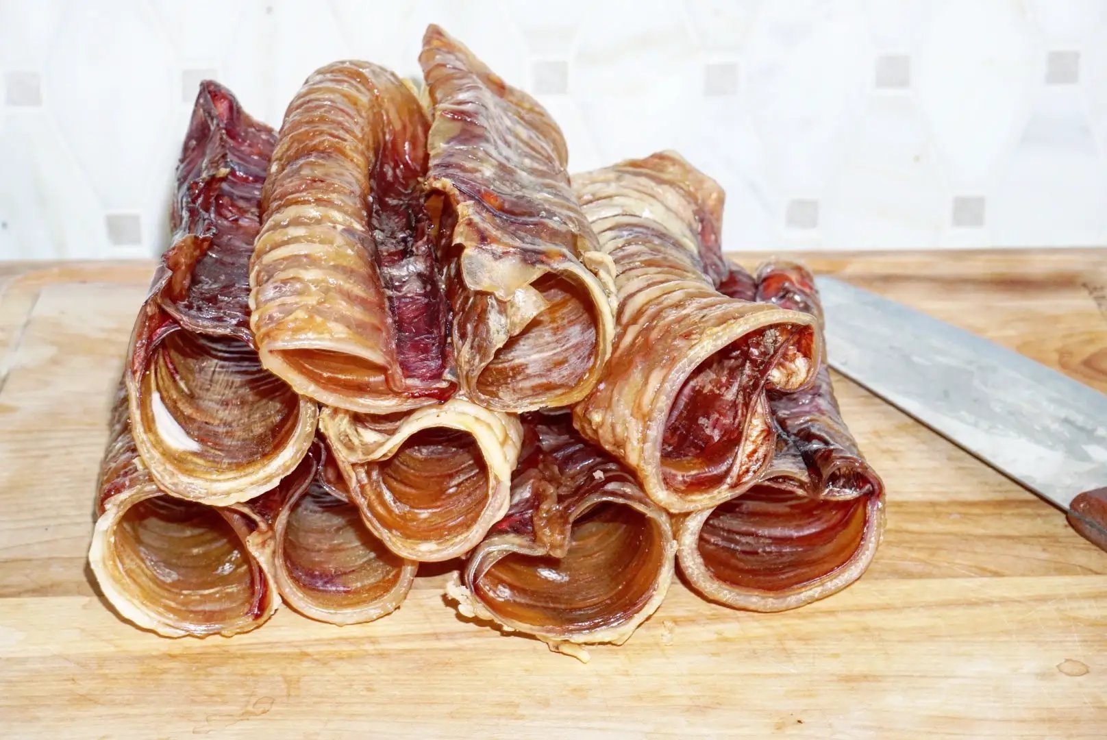 Naked Beasts Beef Trachea chews, grass-fed & finished, stacked rolled tubes on board (multiple pieces)