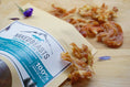 Load image into Gallery viewer, Chicken breast fat-trimmed thin-cut dog treats by Naked Beasts in a beige pouch with a blue label and dried morsels.
