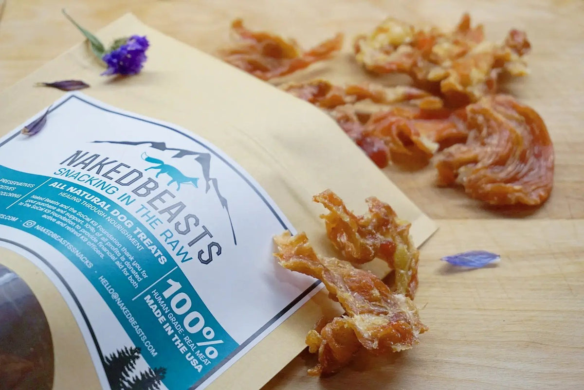 Chicken breast fat-trimmed thin-cut dog treats by Naked Beasts in a beige pouch with a blue label and dried morsels.