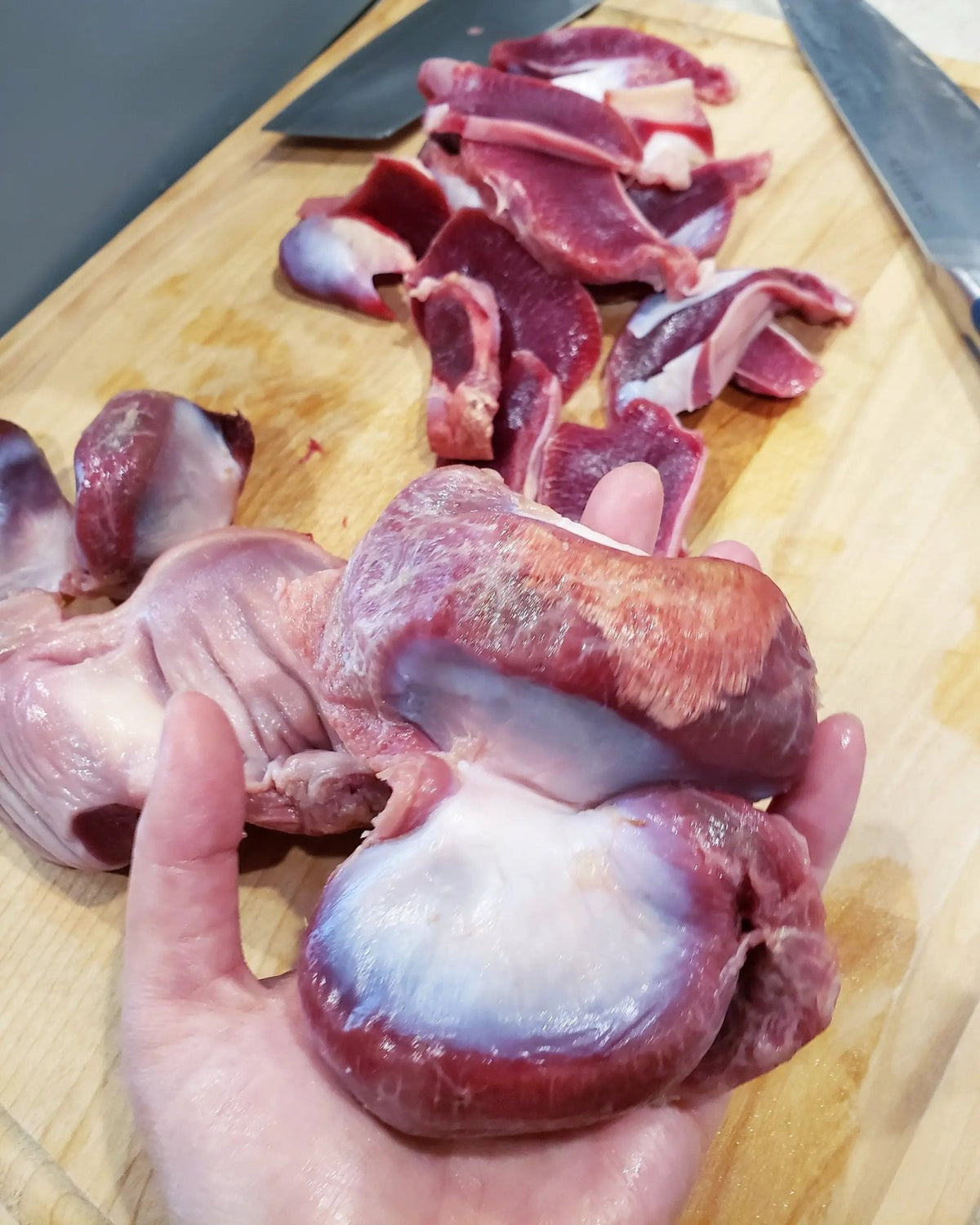Turkey gizzards (ABF), thin-cut, raw pieces on a wooden cutting board