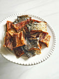 Carica l'immagine nel visualizzatore della galleria, Salmon Fillet pieces by Naked Beasts, smoked and dried with crispy skin on a white plate
