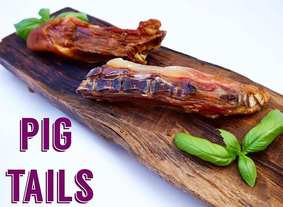 Two pork tails from Naked Beasts on a wooden board with fresh basil.