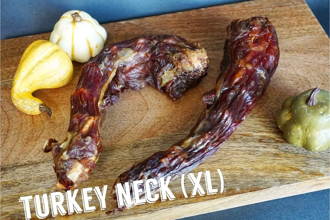 Two XL dried turkey necks on a wooden board with small gourds nearby.