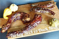 Load image into Gallery viewer, Duck necks on a wooden board; several dark, cured jerky pieces.
