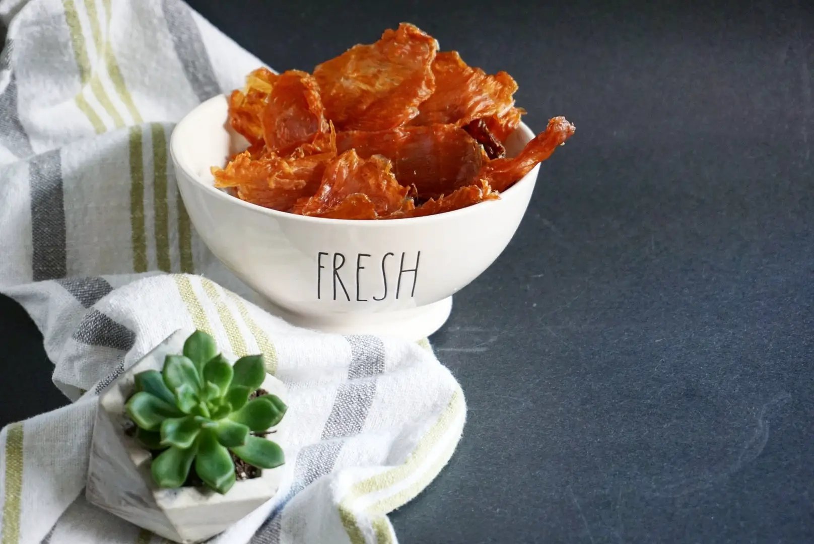 Turkey Breast Thin Cut jerky slices in a white bowl with a striped towel