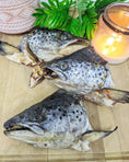 Carica l'immagine nel visualizzatore della galleria, Salmon head halves, 2 pieces, Naked Beasts, silver-gray fish on a wooden board with a candle and greenery.
