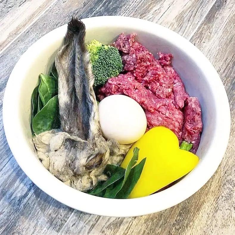 Lamb Ears (Furry & Non-Fur) by Naked Beasts; bowl includes raw meat, a white egg, broccoli, greens, and a yellow heart-shaped item