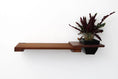 Load image into Gallery viewer, Cat wall shelf with planter: dark wood cat perch extending left, right-side planter housing a leafy plant.
