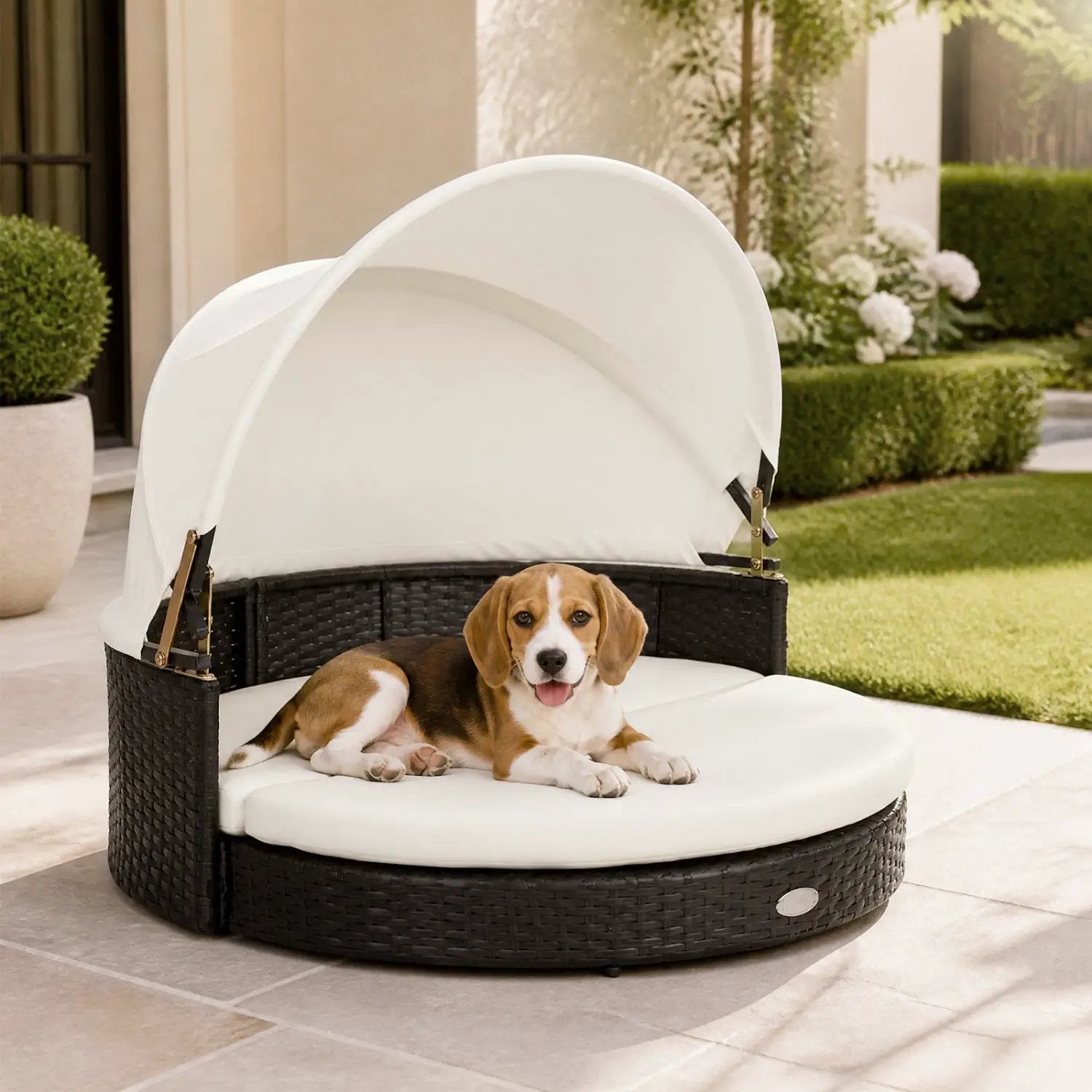 Wicker Dog House with Retractable Canopy and Cushion; round dark wicker base with white canopy outdoors, dog resting