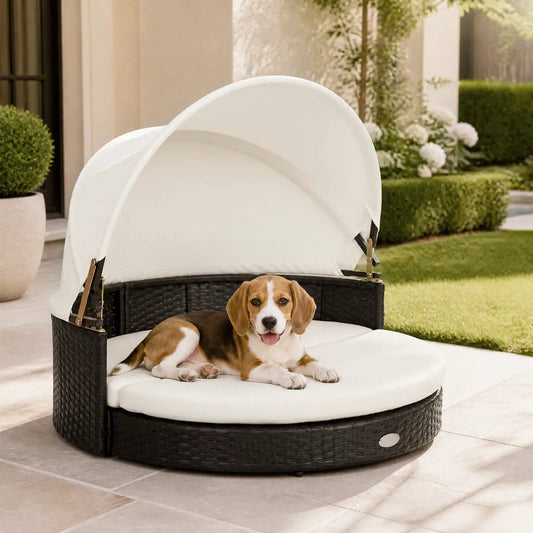 Wicker Dog House with Retractable Canopy and Cushion; round dark wicker base with white canopy outdoors, dog resting