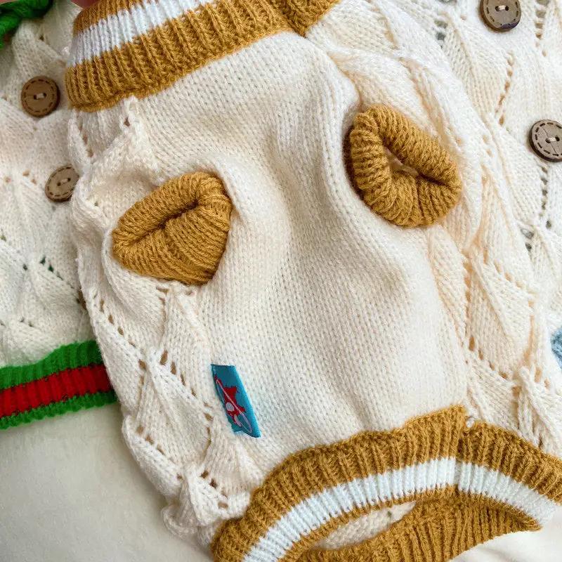 Hollow-out knitted dog sweater by Pet Zen in cream with brown heart patches and striped trim.