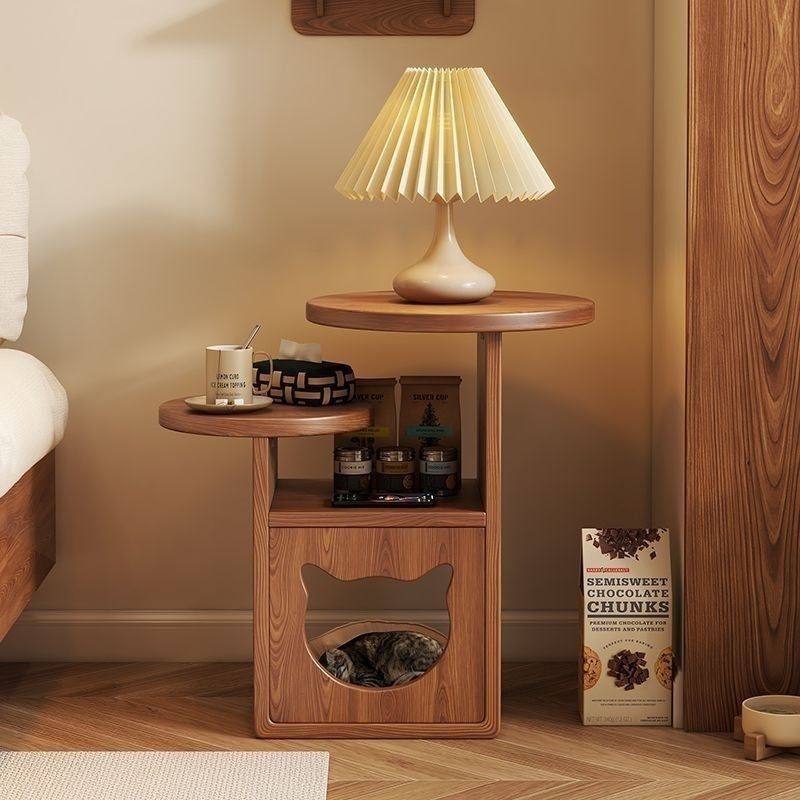 Pine side table with lower cat hideaway beside a bed