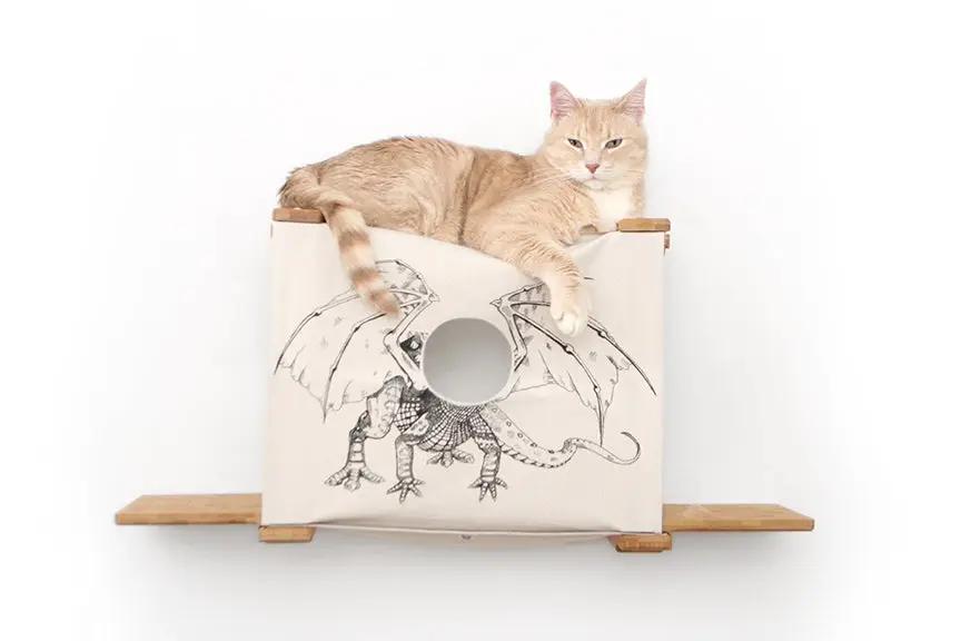 Cat Cubby for Wall - Covered Cat Bed by Catastrophic Creations; beige fabric cube with circular entry on wood shelves, cat lounging.